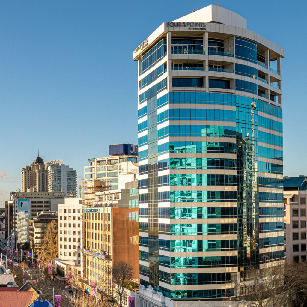 Tall glass-clad building in Auckland city centre, Four Points by Sheraton hotel, retrofitted with Passive Fire NZ’s compliant fire-stopping systems during live hotel operation.