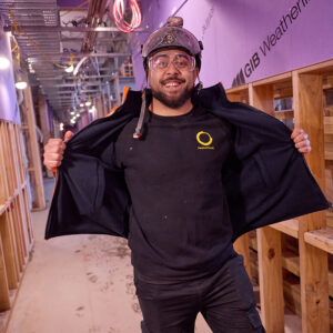 Passive Fire NZ team member proudly displaying company-branded uniform on a commercial construction site.