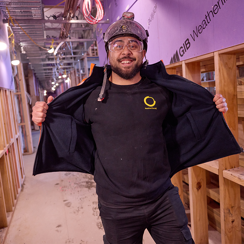 Passive Fire NZ team member proudly displaying company-branded uniform on a commercial construction site.