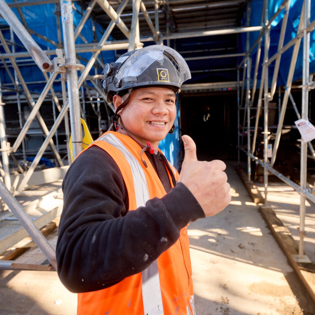 Passive Fire NZ worker smiling and giving thumbs up at a construction site, showcasing industry certification and safety gear